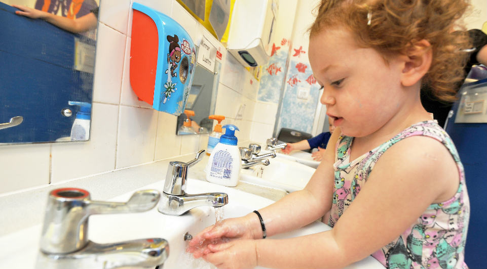 Young pre-school girl learning to wash her hands